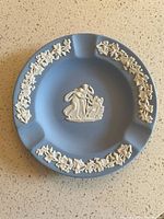 Front view showing blue ashtray with white relief border and center motif