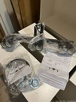 Two black metal wall sconces with two light sockets each, wrapped in plastic on a table with instruction sheets and parts.