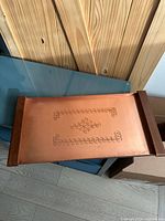 Top view of copper serving tray showing embossed decorative pattern and wood handles at short ends.