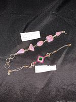 Both bracelets laid on a black fabric, showing copper turquoise stones bracelet with various shapes and the ruby/diopside stone centerpiece bracelet