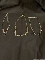 Three necklaces laid out on black fabric showing their full length and bead arrangement