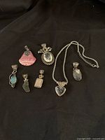 Overview of 8 assorted sterling silver pendants with various gemstones on black cloth background.