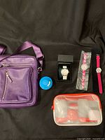 Full lot with purple leather crossbody bag, blue kitchen timer, travel kit in silicone zip bag, and three wrist watches in packaging