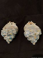 Front view of two shell-shaped Royal Bayreuth porcelain wall pockets showing color, shape, and texture.