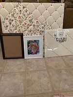Front view of two large French memory boards, one white tufted and one botanical fabric print, along with two picture frames (brown and white with photo)