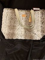 Front view of large plush mocha Snow Bunny Makeup Junkie Bag on black background showing overall size and material texture.