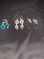 Photo showing three pairs of sterling silver earrings with various gemstone accents on a black fabric surface.