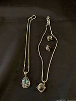 Full set including two necklaces and a pair of earrings, laid out on black fabric