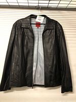 Front view of black leather men's jacket on a hanger, showing zipper, collar, and sleeves.