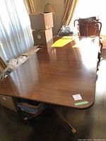 Full view of extended dining table top with two leaves installed, surface showing wear