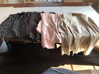 Four ladies jackets laid out flat on a table, showing the range of styles and colors