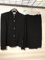 Full view of black knit jacket and skirt on hangers showing overall suit condition and design