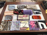 Full lot of 14 scarves arranged on a table showing variety of colors and patterns