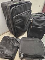 Overview of four luggage pieces: large upright, medium upright, small carry-on and duffel bag