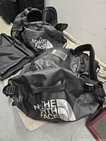 Two black North Face travel bags placed on the floor showing front logos and some wear.