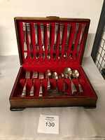 Overall view of open wooden box showing flatware and serving pieces