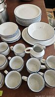 Full set of plates, bowls, mugs, and pitcher arranged on table