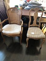 Front view of two vintage wooden chairs with fabric seats and visible wear, the wicker armchair showing broken wicker spots.