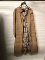 Full front view of beige trench coat showing double-breasted button front