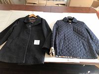 Both coats displayed side by side on table