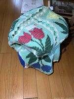 Close up of the folded afghan showing pink tulip flower crochet squares on a pale background.