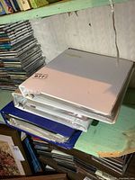 Three binders stacked on a green shelf, seen from above, showing white and blue covers and labeled with an auction lot sticker.