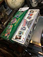Photo showing two boxed sets of Upper Deck baseball cards from 1990 and 1991, positioned side by side on a reflective surface with other room items partially visible.