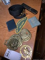 View of all items in lot including badges, belt, patch, mini books, and straight razor case.
