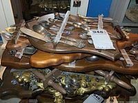 Wooden rack holding multiple metal souvenir spoons with decorative handles and enamel badges