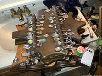 Wooden rack filled with collector spoons laid on sink counter, showing various spoon designs, some with enamel emblems