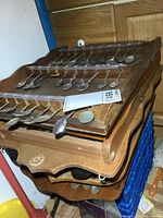 Stacked wooden racks containing multiple collector spoons with varied designs.