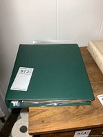 Closed green binder full of comic books on wooden surface