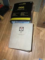 Two closed binders on wooden floor, one black with numbering and yellow decoration, one white with CVIB Employee Attitude Survey logo.