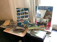 Photo of a collection of postcards and booklets displayed on a table near a window, including a large Statue of Liberty postcard booklet.