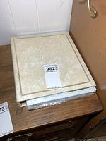 Closed beige binder placed on wooden surface with a visible label.