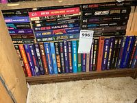 Photo showing multiple Star Trek soft cover paperbacks organized on a bottom shelf with clear titles and authors visible.