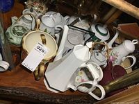 Overview of multiple assorted teapots of various sizes and styles on a wooden surface