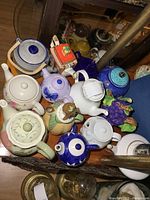 Overview of collection of various teapots in multiple colors and styles placed on shelf