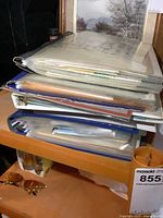 Stack of several binders and folders containing ephemera and books related to Tillsonburg history on a wooden shelf