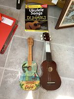 Two ukuleles on floor with Ukulele Songs for Dummies book above them.