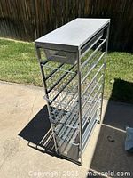Full view of Elfa rack showing metal frame, 5 wire baskets, and light gray countertop outdoors in natural light