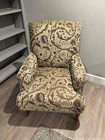 Front view of Norwalk upholstered armchair showing floral patterned fabric, padded armrests, and wooden legs.