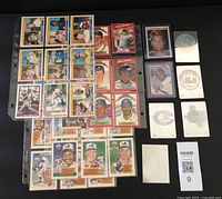 Collection of baseball cards in plastic sleeves showing a variety of players and series from 1980s-1990s, including Topps and holographic cards.