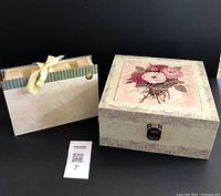Photo showing floral wood and tile hinged storage box and cardboard ribbon paper organizer side by side on black background, with lot number card.