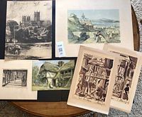 Collection of 6 vintage lithographs and prints arranged on a round wooden table showcasing various scenes including architecture and landscapes.