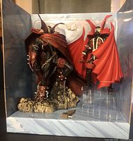 Two Spawn McFarlane figures still in original packaging showing detailed figures and sculpted base with skulls and chains.