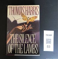 Front cover of hardcover novel with dust jacket, showing author, title, and moth illustration.