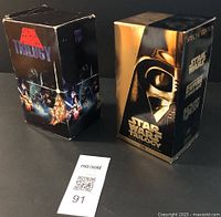 Two VHS tape box sets of the Star Wars trilogy showing front and side views, one standard edition and one special edition with Darth Vader artwork.