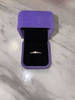 Front view of the sterling silver ring with cubic zirconia stones in purple ring box.