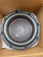 Close-up of Audiopipe subwoofer cone showing black cone with red stitching and Audiopipe logo.